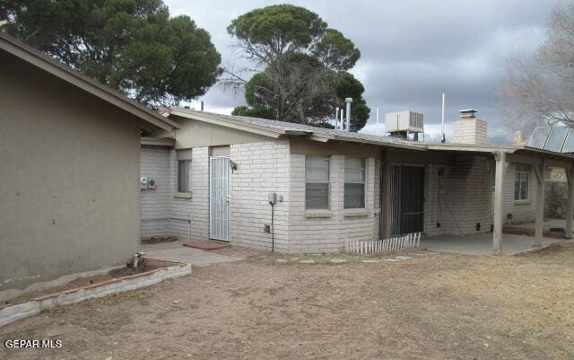 rear view of property with a patio, central AC, and a chimney