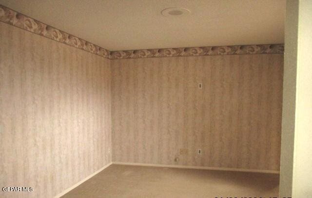 empty room featuring baseboards, carpet flooring, and wallpapered walls