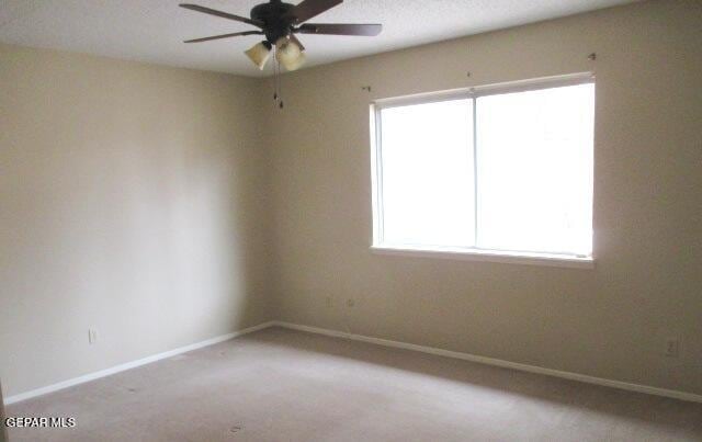 carpeted empty room featuring ceiling fan and baseboards