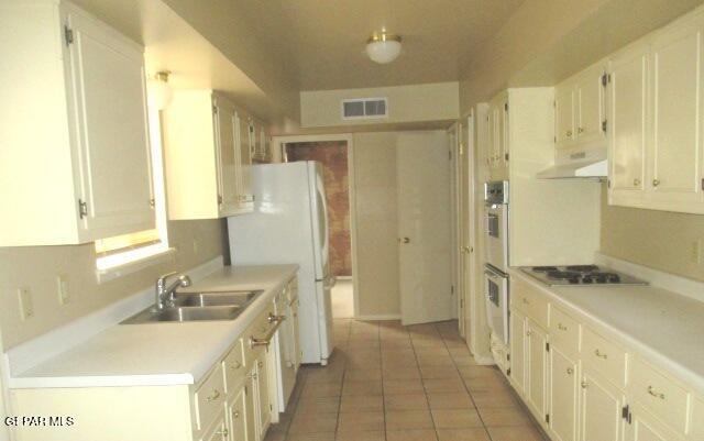 kitchen with under cabinet range hood, a sink, visible vents, white cabinets, and cooktop