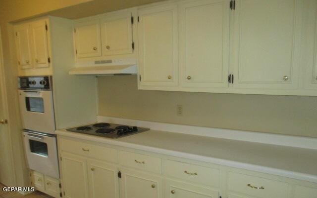 kitchen with white double oven, under cabinet range hood, electric cooktop, white cabinetry, and light countertops