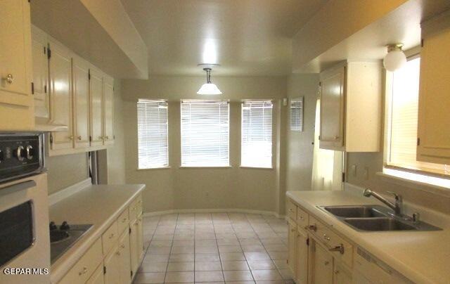 kitchen with a healthy amount of sunlight, light countertops, a sink, and oven