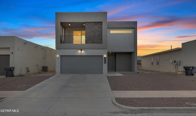 modern home with a balcony, central air condition unit, stone siding, concrete driveway, and stucco siding