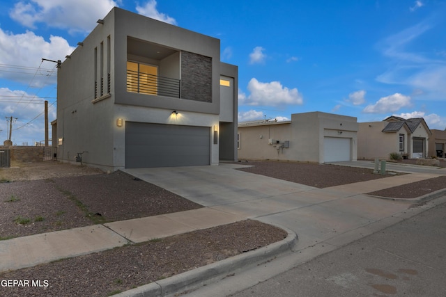 view of front of home with a balcony, central AC unit, concrete driveway, and stucco siding