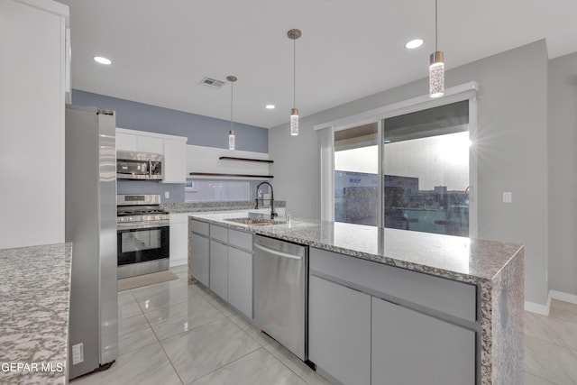 kitchen with hanging light fixtures, appliances with stainless steel finishes, white cabinetry, a sink, and light stone countertops