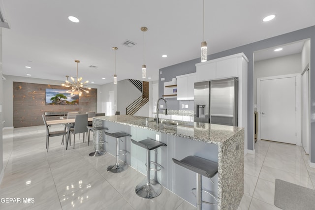 kitchen featuring stainless steel fridge, visible vents, white cabinets, a sink, and recessed lighting