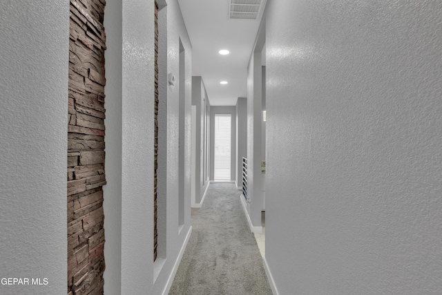 corridor with recessed lighting, visible vents, a textured wall, carpet flooring, and baseboards