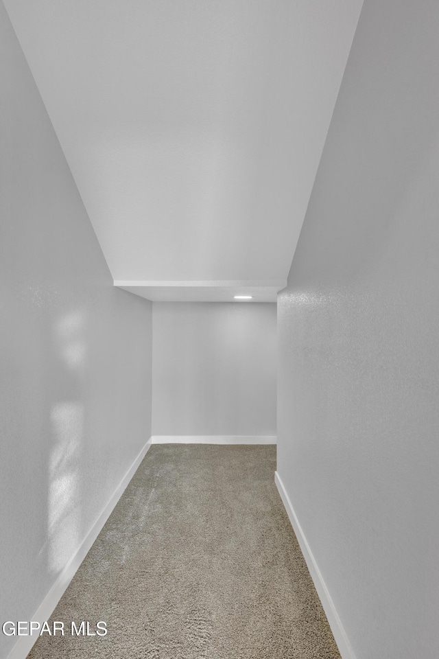 interior space featuring lofted ceiling, carpet floors, and baseboards