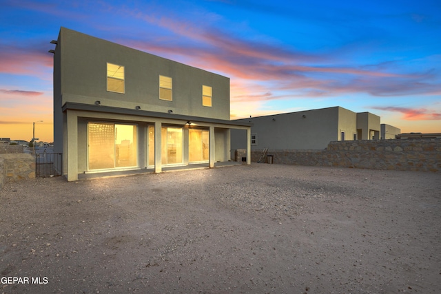 rear view of house featuring fence and stucco siding