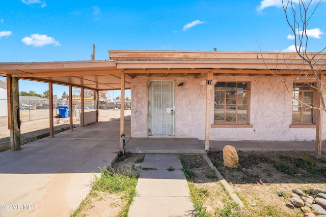 property entrance featuring an attached carport, concrete driveway, and stucco siding