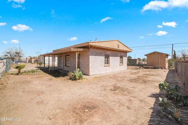 view of property exterior with a storage shed, a fenced backyard, an outbuilding, and stucco siding