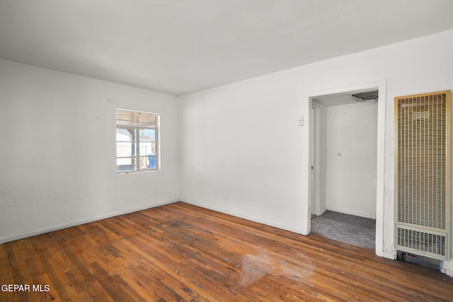 unfurnished room with a heating unit and hardwood / wood-style flooring