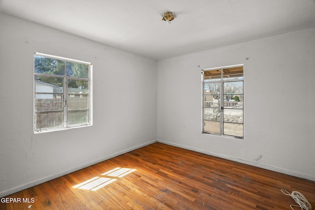 unfurnished room with plenty of natural light, baseboards, and wood-type flooring