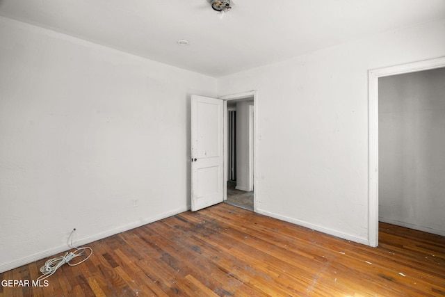 spare room with baseboards and wood-type flooring