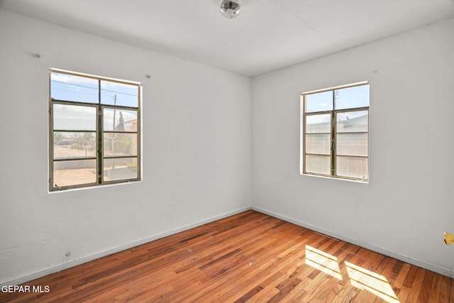 unfurnished room with plenty of natural light, baseboards, and hardwood / wood-style flooring