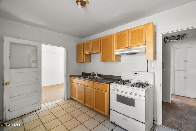 kitchen featuring under cabinet range hood, dark countertops, white gas range oven, and a sink