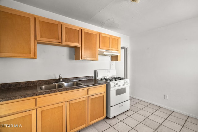 kitchen with light tile patterned floors, white range with gas cooktop, a sink, under cabinet range hood, and dark countertops