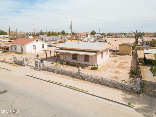 view of front of property featuring an outbuilding, a storage unit, a fenced front yard, and stucco siding