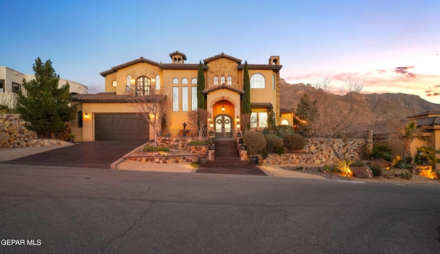 mediterranean / spanish house with aphalt driveway, french doors, a chimney, and stucco siding