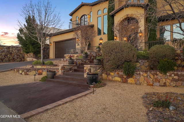 view of front of property featuring stucco siding, a tiled roof, an attached garage, and driveway