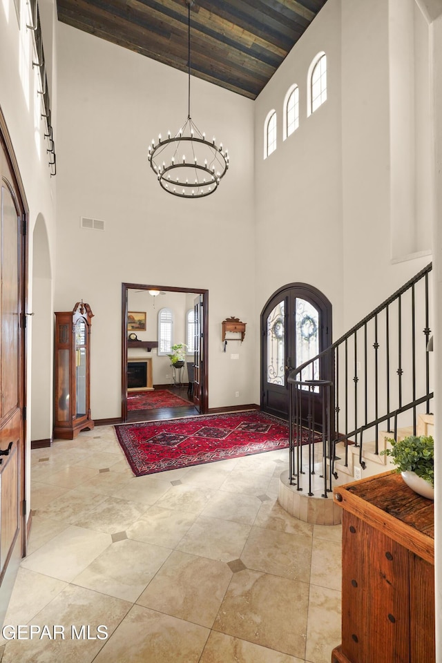 entryway featuring stairs, a notable chandelier, a healthy amount of sunlight, and arched walkways