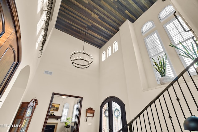 interior space with visible vents, arched walkways, wood ceiling, french doors, and a notable chandelier