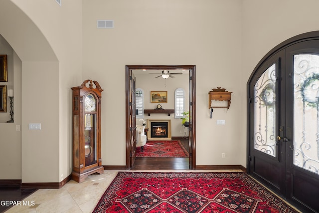entryway featuring visible vents, french doors, arched walkways, and a towering ceiling