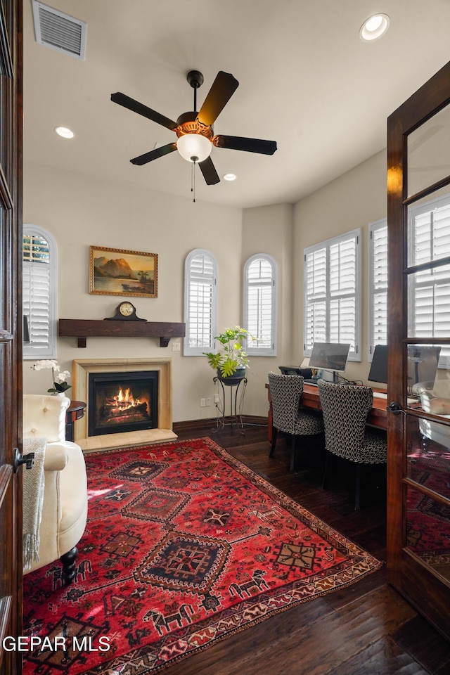 living area featuring hardwood / wood-style floors, visible vents, a glass covered fireplace, and recessed lighting