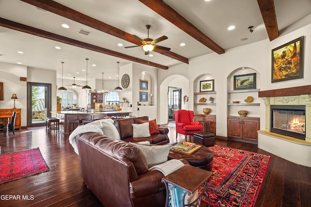 living area with dark wood finished floors, plenty of natural light, visible vents, and a high end fireplace