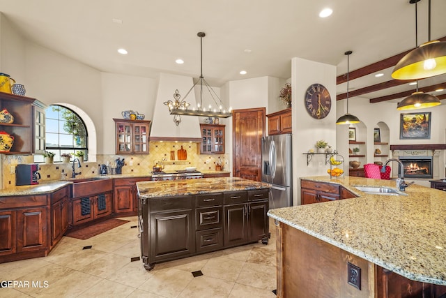 kitchen with a sink, backsplash, a lit fireplace, and stainless steel refrigerator with ice dispenser