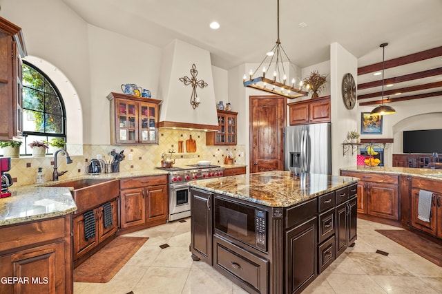 kitchen with custom exhaust hood, decorative backsplash, appliances with stainless steel finishes, and a sink