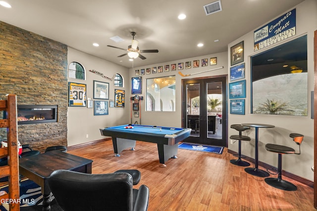 game room featuring visible vents, a stone fireplace, wood finished floors, and french doors