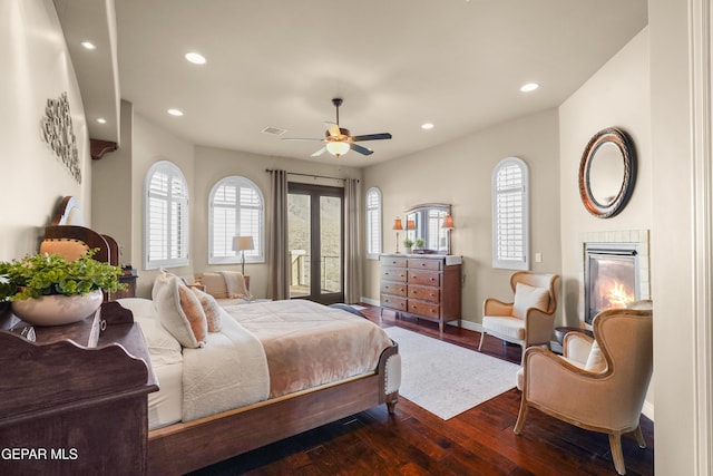 bedroom featuring visible vents, baseboards, dark wood finished floors, a tiled fireplace, and recessed lighting