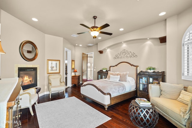 bedroom featuring a glass covered fireplace, recessed lighting, visible vents, and dark wood-style flooring
