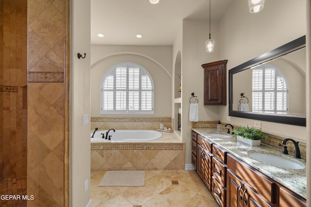 full bathroom featuring a sink, a wealth of natural light, a bath, and double vanity