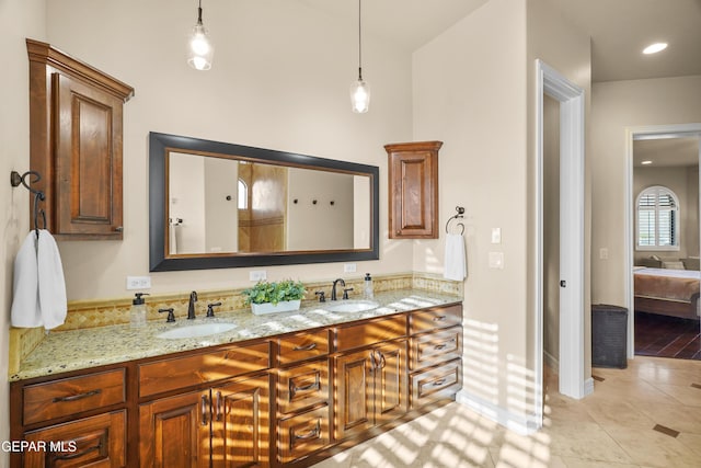 ensuite bathroom with double vanity, tile patterned flooring, ensuite bath, and a sink