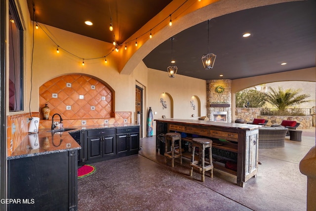 view of patio / terrace featuring outdoor wet bar, area for grilling, an outdoor living space with a fireplace, and a sink