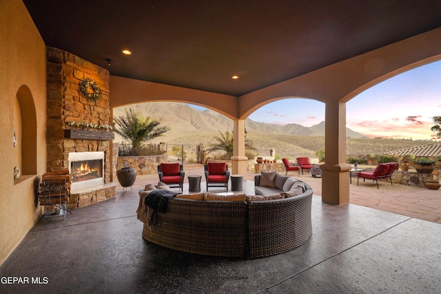 view of patio / terrace featuring a mountain view, an outdoor living space with a fireplace, and fence