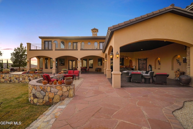 back of house with an outdoor living space, a balcony, a patio area, and stucco siding