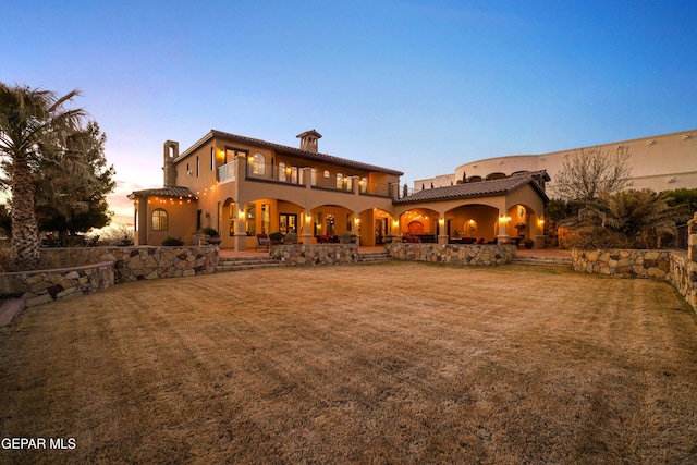 rear view of house with a yard, a patio, and a balcony