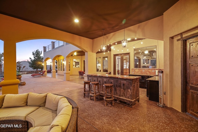 bar with ornate columns, decorative light fixtures, arched walkways, and backsplash