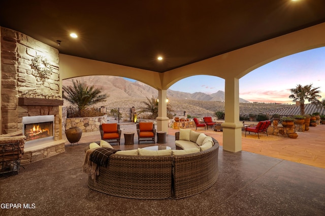 view of patio / terrace with a mountain view, an outdoor living space with a fireplace, and fence