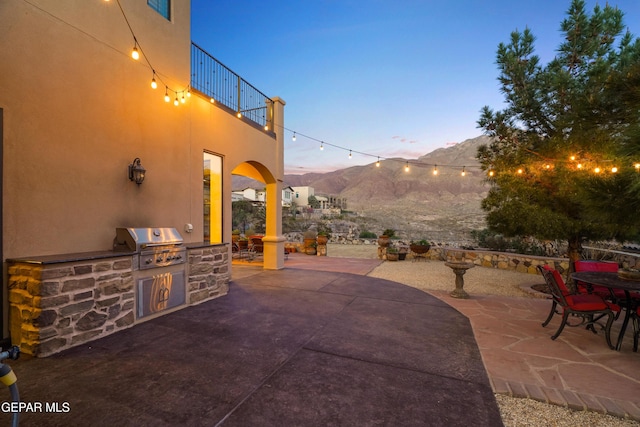 view of patio / terrace with a mountain view, an outdoor kitchen, a grill, and a balcony