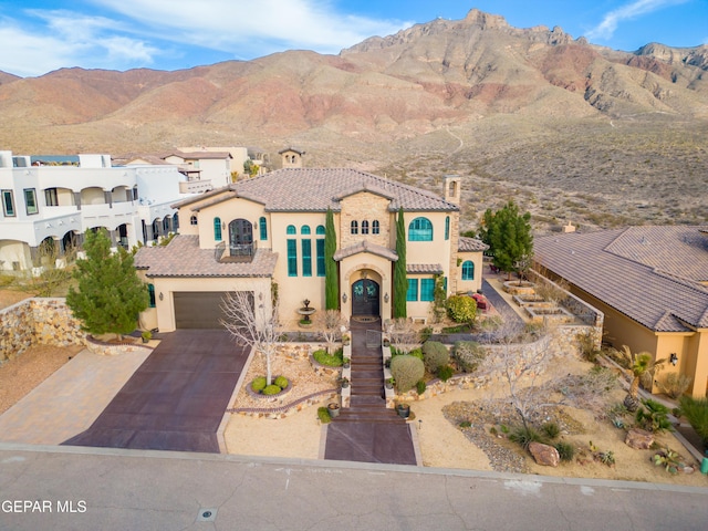 mediterranean / spanish-style home with stucco siding, a balcony, driveway, and a tile roof