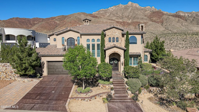1408 Via Quijano Ln, El Paso, TX 79912 - mediterranean / spanish-style home with stucco siding, concrete driveway, a tiled roof, a mountain view, and a garage