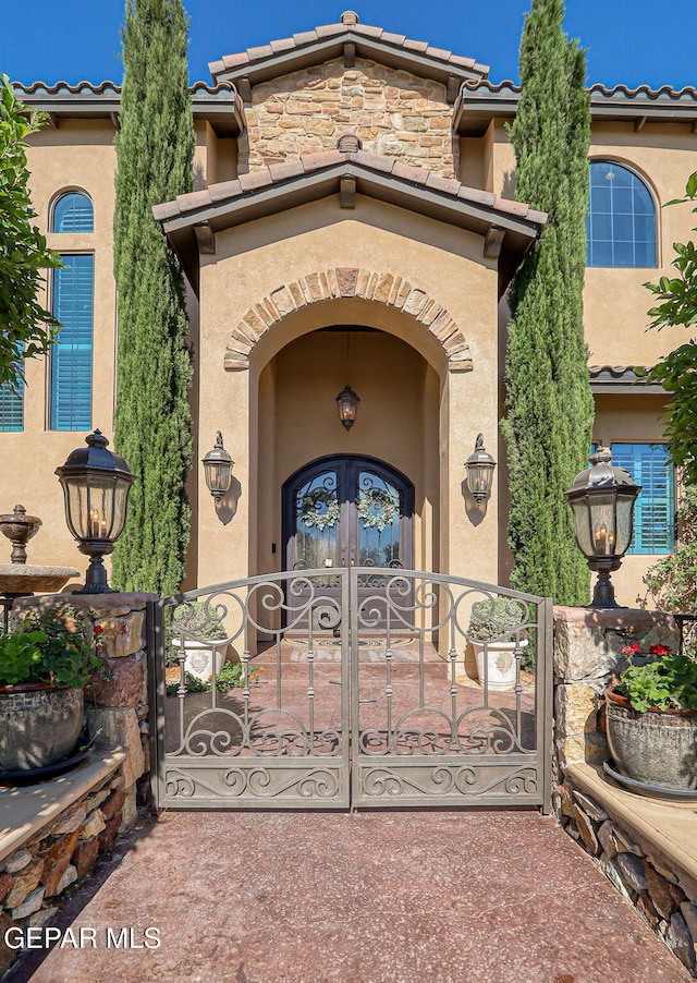 1408 Via Quijano Ln, El Paso, TX 79912 - entrance to property with stucco siding, a gate, french doors, and a tiled roof