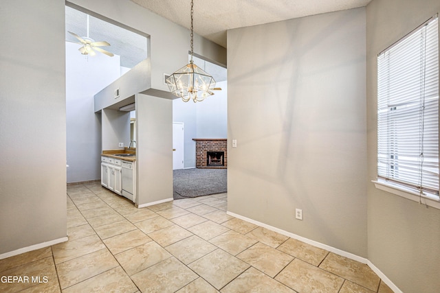 kitchen with pendant lighting, ceiling fan with notable chandelier, a sink, a fireplace, and dishwasher