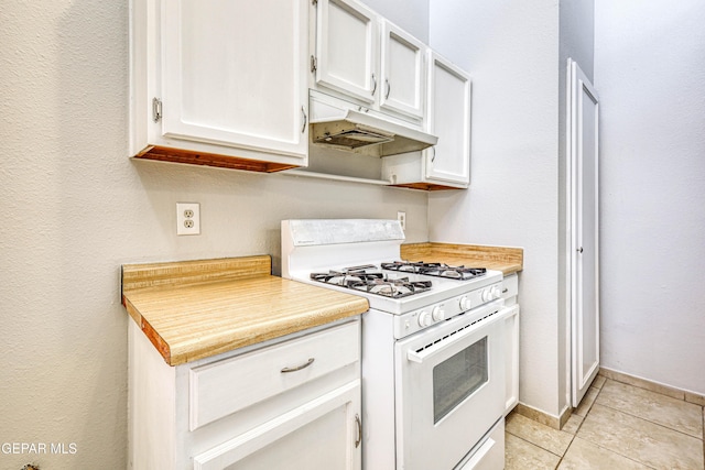 kitchen featuring light tile patterned floors, light countertops, under cabinet range hood, white cabinetry, and white gas range