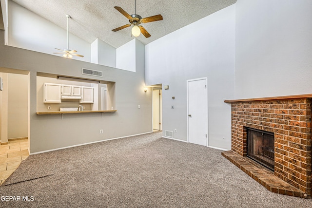 unfurnished living room featuring visible vents, light colored carpet, a fireplace, and a textured ceiling