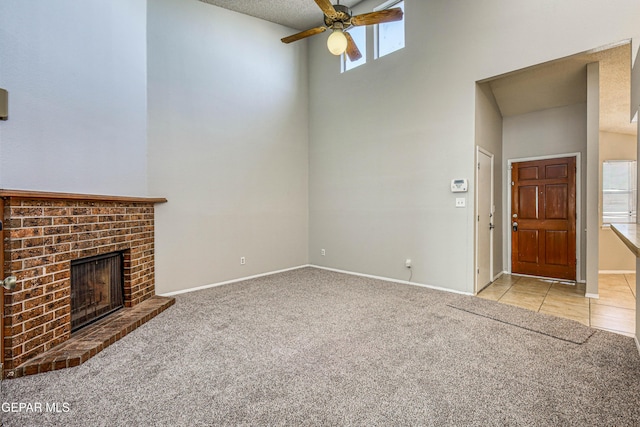 unfurnished living room featuring baseboards, light colored carpet, light tile patterned floors, a fireplace, and a high ceiling